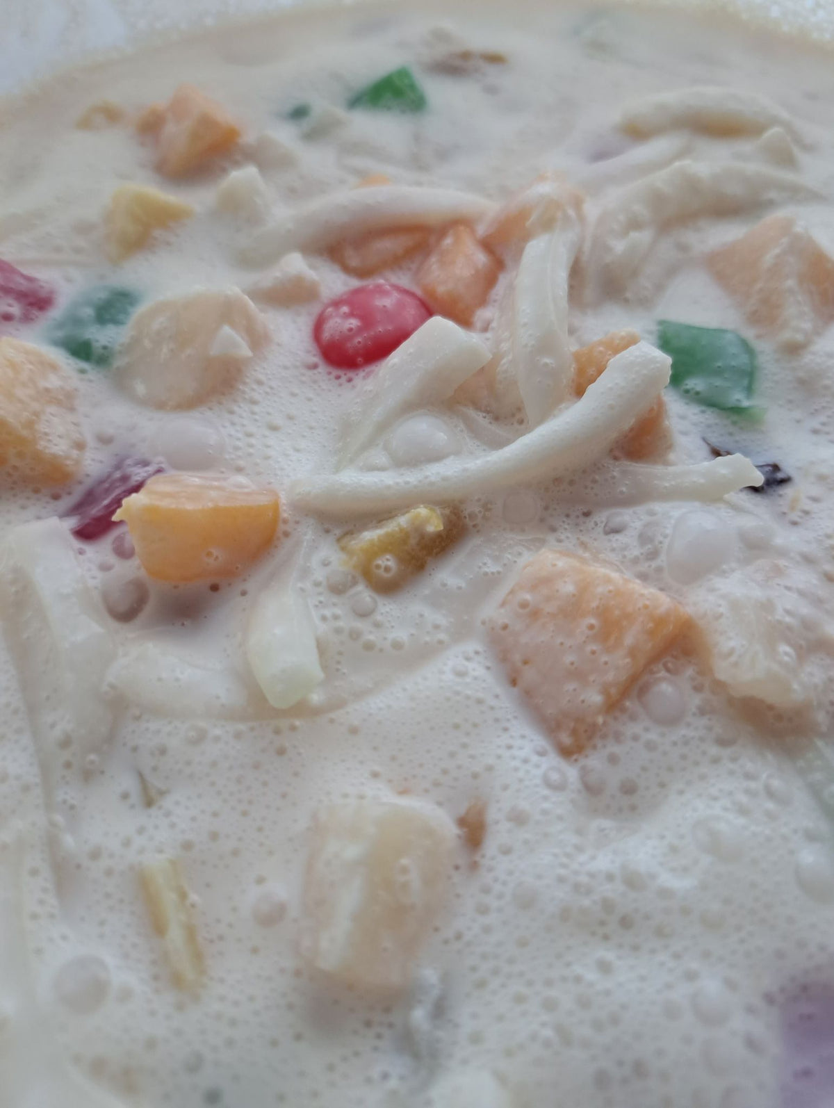 Close-up of creamy fruit salad with coconut strips and colourful fruit