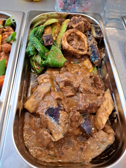Beef kare-kare with vegetables in a stainless-steel catering tray
