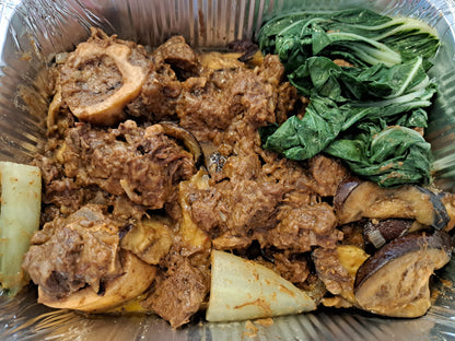 Close-up of beef kare-kare with marrow bones, bok choy and aubergine