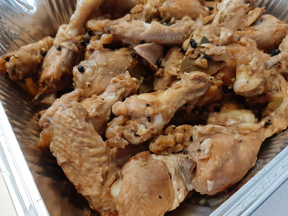 Close-up of tender chicken adobo with peppercorns and bay leaves