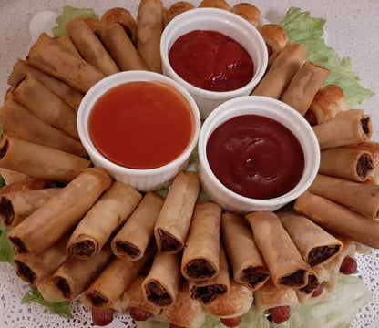 Cooked chicken mini lumpia platter arranged around dipping sauces