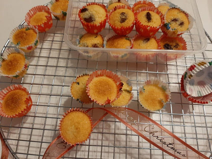 Golden coconut macaroons cooling in red paper cases on a wire rack