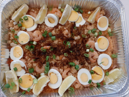 Pancit palabok tray garnished with sliced eggs, spring onions and lemon wedges