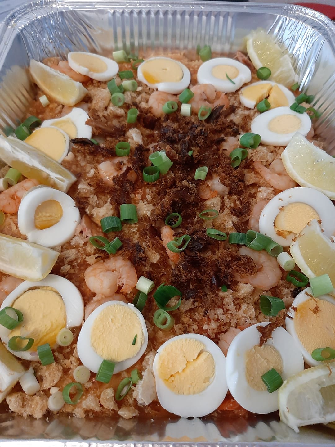 Large pancit palabok tray with boiled eggs, spring onions and lemon