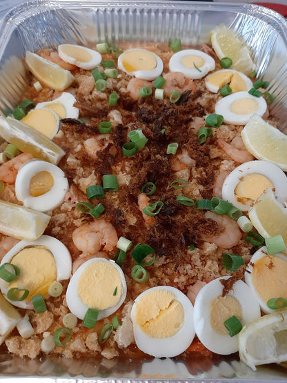 Large pancit palabok tray with boiled eggs, spring onions and lemon