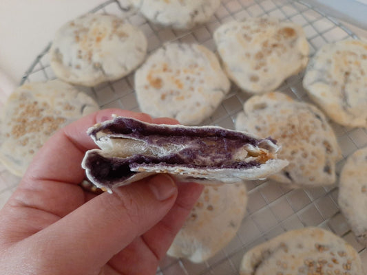 Ube piaya split open to show the smooth purple yam filling
