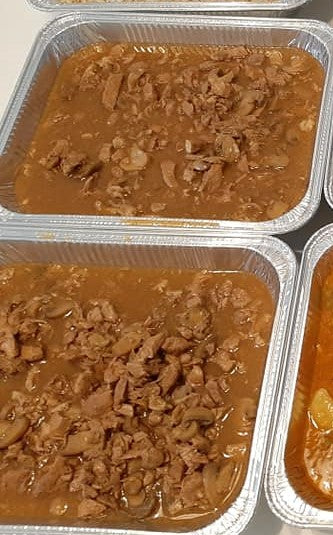 Two large trays of saucy pork asado ready for a gathering