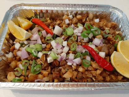 Pork sisig tray topped with red onion, spring onion, chillies and lemon