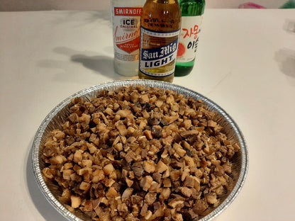 Large bowl of chopped pork sisig served beside bottled beer