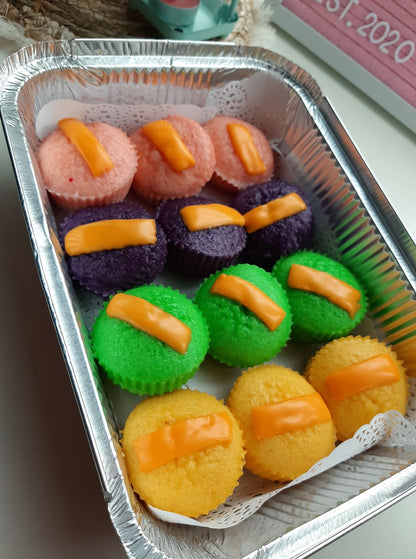 Rows of colourful puto cheese topped with orange cheese slices