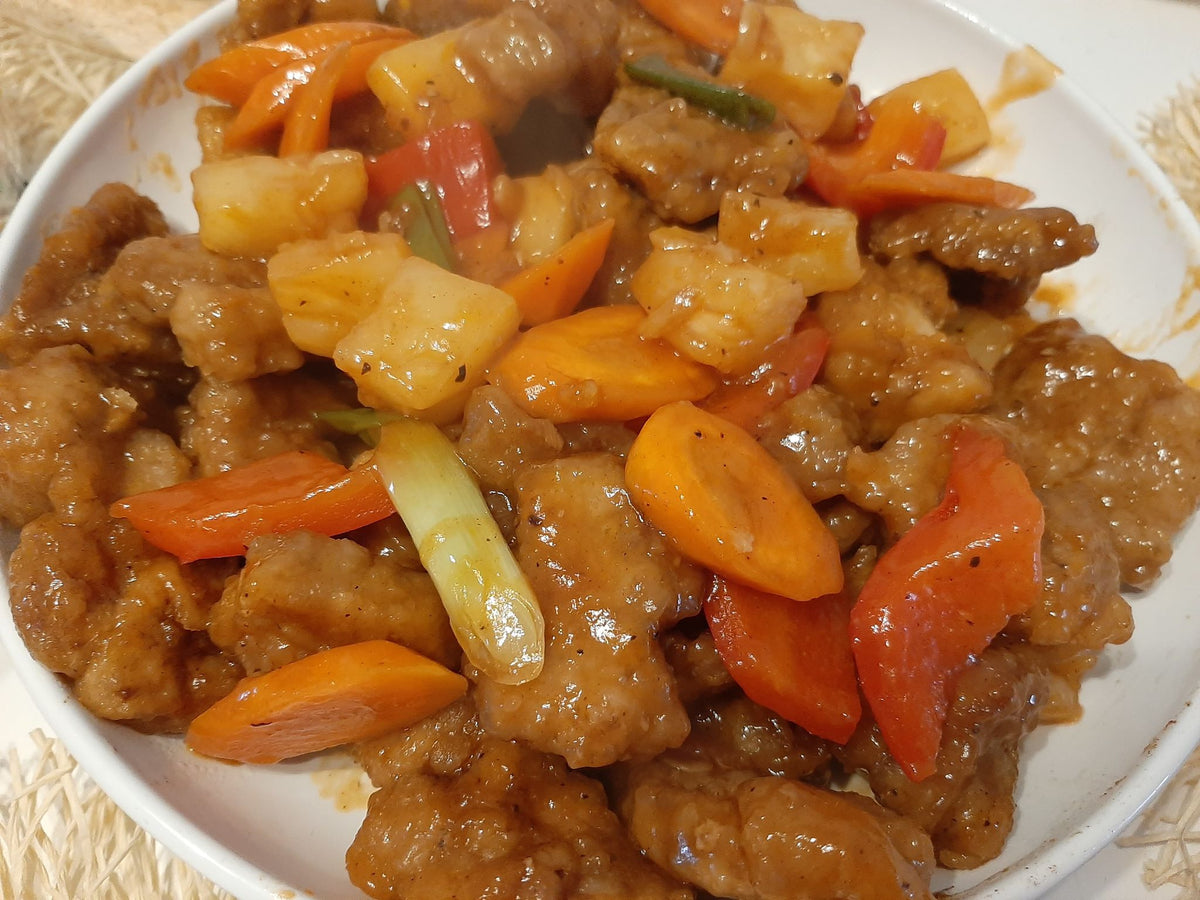 Sweet and sour pork with pineapple, carrots and bell peppers served in a bowl