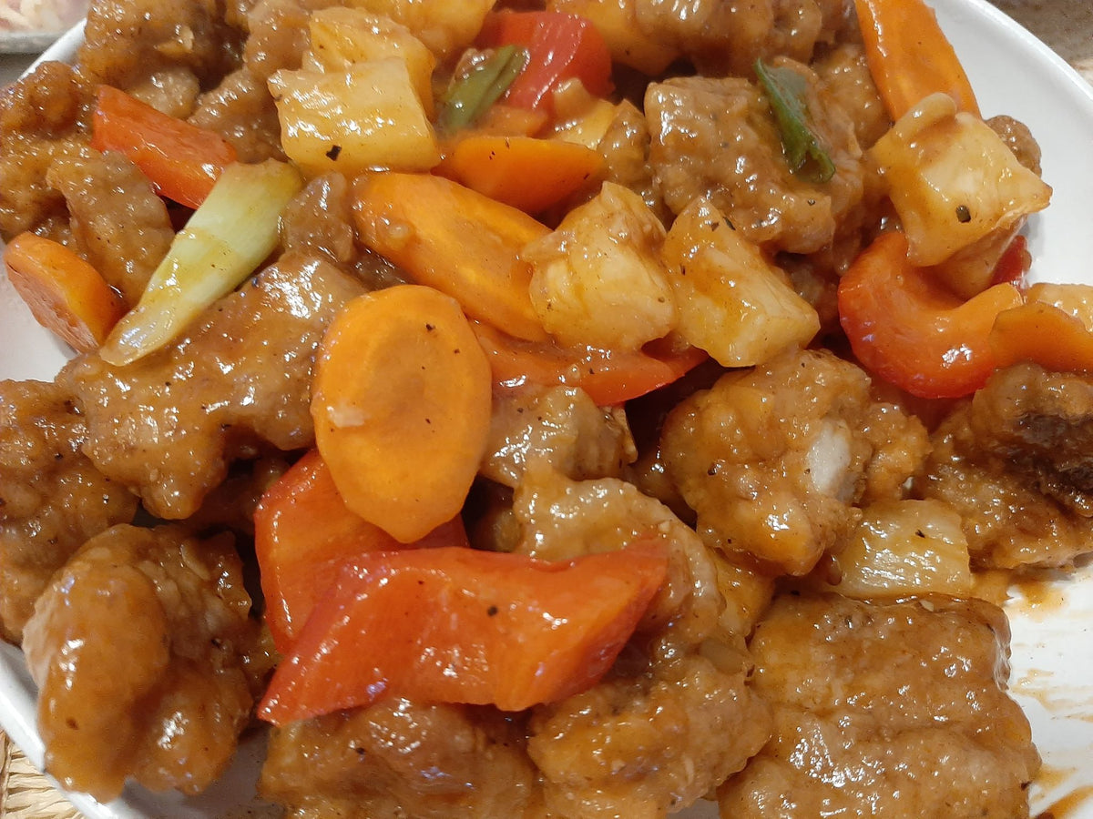 Close-up of sweet and sour pork with pineapple, carrots and bell peppers