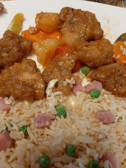 Sweet and sour pork with pineapple served alongside fried rice with peas and ham